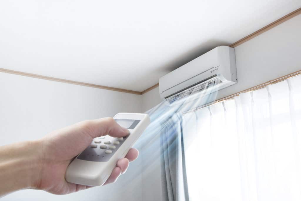 hand holding remote pointing at unit with cold air blowing out