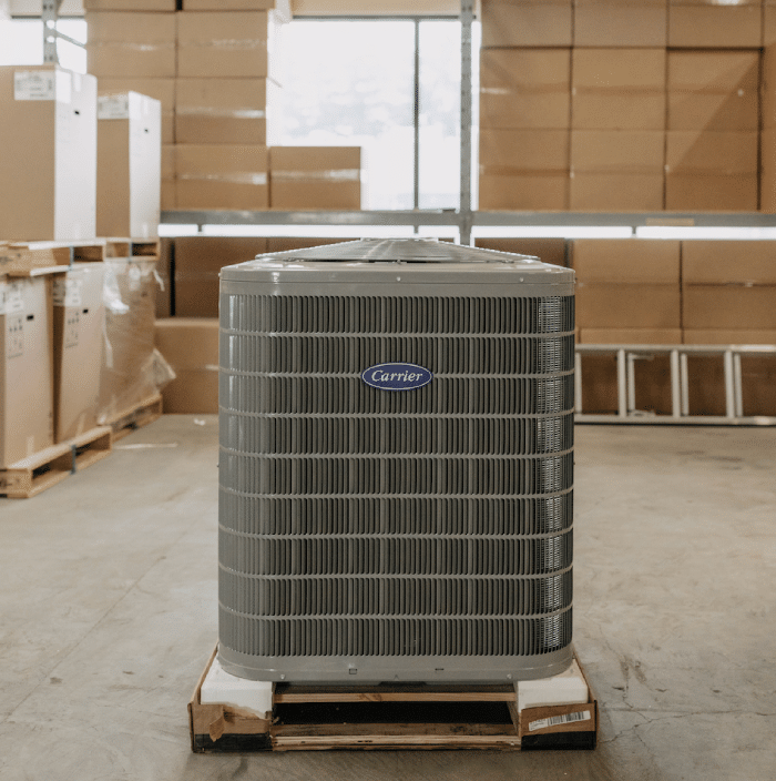 New home hvac unit outdoor condenser fan unit made by carrier on pallet in warehouse