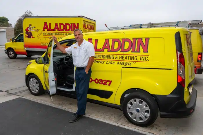 Aladdin air conditioning service technician standing next to yellow and red aladdin HVAC work van