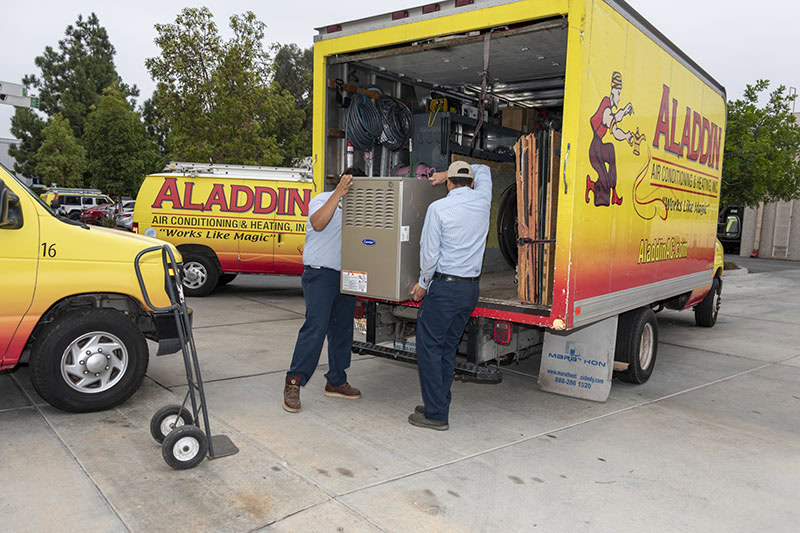 Aladdin HVAC technicians removing equipment from the back of company branded truck.