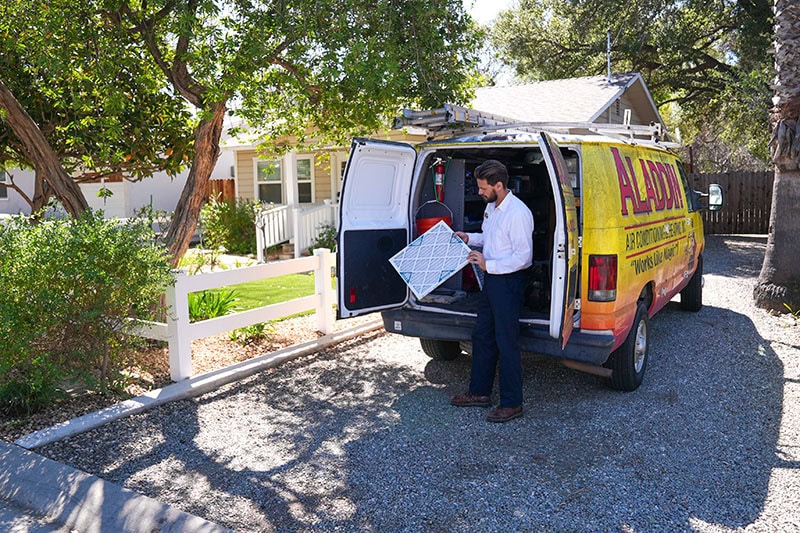 Everything You Need to Know About HVAC Filters. An employee holding a filter by their company van.